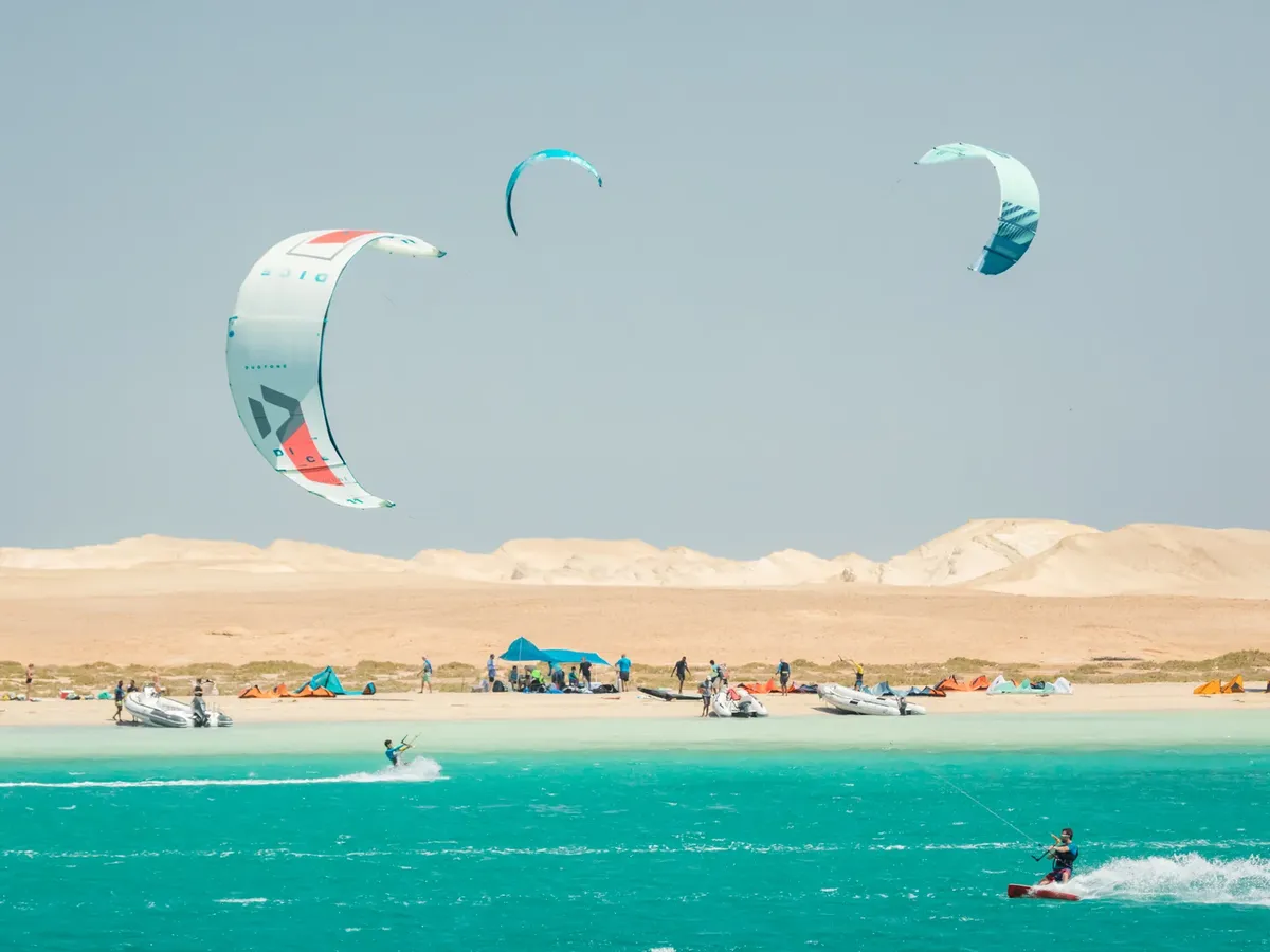 Kitecamp Ägypten: türkises Flachwasser vor der Wüstendüne im Roten Meer, Kites am Himmel