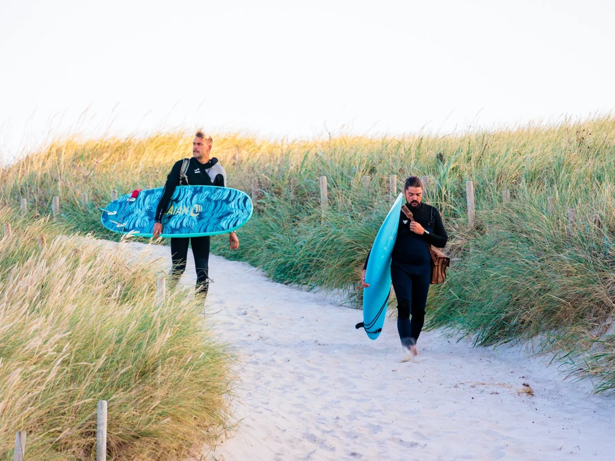 Kitecamp Dänemark: zwei Teilnehmer tragen ihre Boards den Dünenpfad zum Strand hinunter